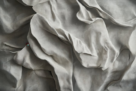 A close-up of wrinkled fabric with a subtle texture, showcasing the interplay of light and shadow.の素材