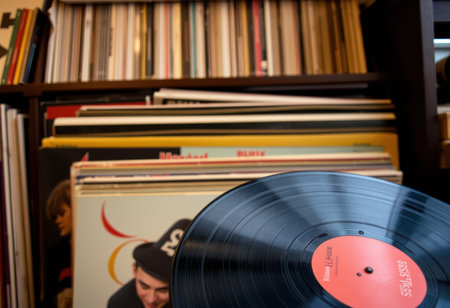 A black vinyl record sits on a shelf full of other records.の素材
