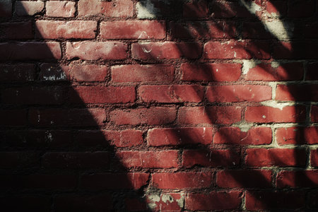 A close-up shot of a red brick wall with sunlight casting shadows and creating interesting patterns.の素材