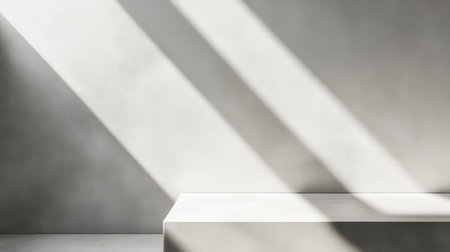 A minimalist white platform with diagonal sunbeams casting shadows on a white wall, providing a clean and simple backdrop.の素材