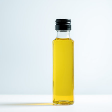 A single bottle of golden yellow cooking oil stands on a white background, showcasing its clear glass and simple design.の素材