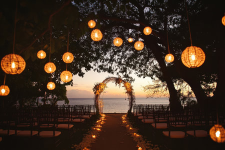 A romantic beach wedding ceremony setup with a flower arch, lanterns, and a petal-lined aisle.の素材