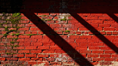 Bright sunlight illuminates the rough, deep red brickwork, emphasizing the deterioration and patches of bright green moss, sharply divided by wide, dark diagonal shadows.の素材