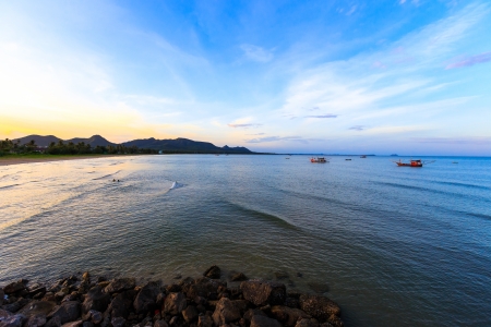sunset with boat fishing on sea  and mountain backgroundの写真素材