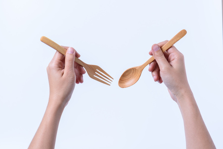 hand holding fork and wooden spoon isolated on white backgroundの写真素材