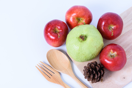 pipe cone ,red apple,guava and fork and wooden spoon on white backgroundの写真素材