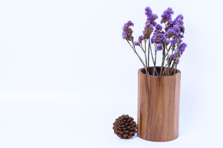 pine cone  and wood vase classic with a bouquet of purple flowers on white backgroundの写真素材