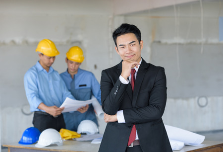 businessman standing smart in front of engineer architectural project and hand holding blueprintの写真素材