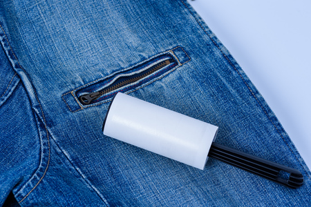 Adhesive roller for cleaning clothes from animal fur and hair isolated on blue denim jeanの写真素材