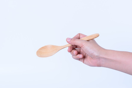 hand holding wooden spoon on wood on white backgroundの写真素材
