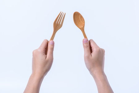 hand holding fork and wooden spoon isolated on white backgroundの写真素材