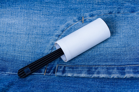 Adhesive roller for cleaning clothes from animal fur and hair isolated on blue denim jeanの写真素材