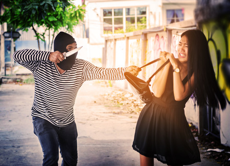 woman wearing dress black walking on street and criminal sackの写真素材
