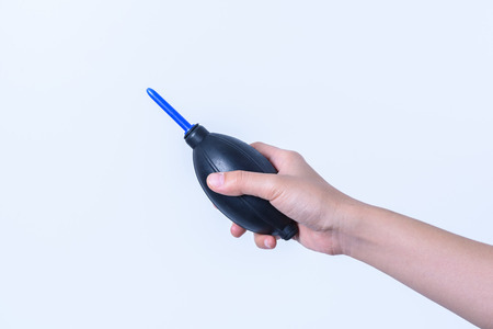 hand holding black rubber ball for cleaning camera lens on white backgroundの写真素材