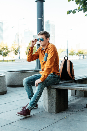 Stylishly dressed young man on the streets of Warsaw. The guy in the city center. Travel the European city. Man with a briefcase.の写真素材