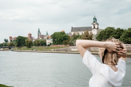 A young woman on the Vistula River in Krakow. Stylish girl in sunglasses talks on her phone. View of the city of Krakow.の写真素材
