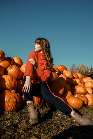 Young woman on a pumpkin farm. Beautiful girl near pumpkins. A girl with a pumpkin