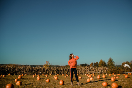Young woman on a pumpkin farm. Beautiful girl near pumpkins. A girl with a pumpkin