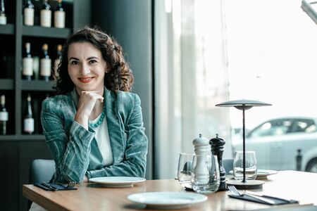 Stylish woman at table in restaurant. Young lady chooses wine. Restaurant with wine. Sommelier. Taster.の写真素材