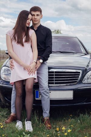 Cute young couple near the car. The guy and the girl are in love. Family and their car. In Poland.