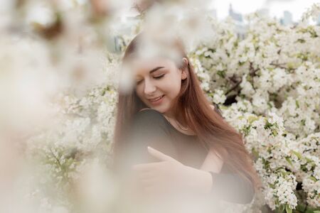 Beautiful girl in white flowers. Woman posing in white flowers. Plenerの写真素材