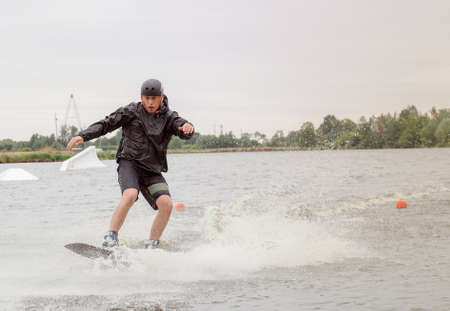 Bielawa, Polska. 03/06/2020 Wawa Wake. Bielawa, Polska. 03/06/2020 Wawa Wake. Athlete guy rides on a wakeboard. A man in sportswear swims on a lake in a wakeboard park. Sportのeditorial素材