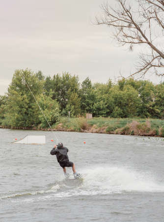 Bielawa, Polska. 03/06/2020 Wawa Wake. Bielawa, Polska. 03/06/2020 Wawa Wake. Athlete guy rides on a wakeboard. A man in sportswear swims on a lake in a wakeboard park. Sportのeditorial素材