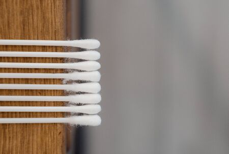 White cotton swabs on the edge of a wooden table.