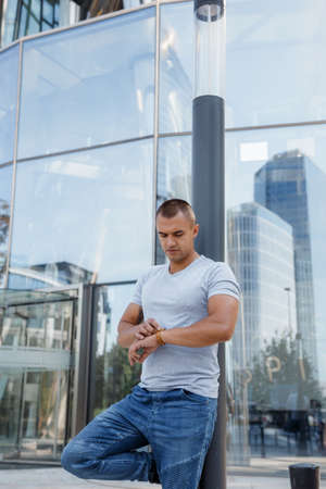 Young man with a watch. The guy looks at what time on his watch.Young man with a watch. The guy looks at what time on his watch. A man in the city.のeditorial素材