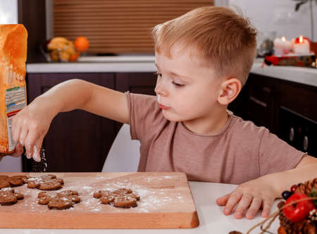 Little boy painting gingerbread man. Handmade Christmas gift ideas. Kitchen decorated for Christmas.の写真素材