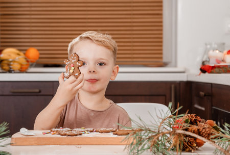 Boy holding a tray full of homemade gingerbread cookies. Kids bake Christmas cookies. little caucasian kid eating a bite of a chocolate ginger Christmas cookie.の写真素材