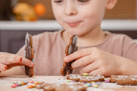 Boy holding a tray full of homemade gingerbread cookies. Kids bake Christmas cookies. little caucasian kid eating a bite of a chocolate ginger Christmas cookie.の写真素材