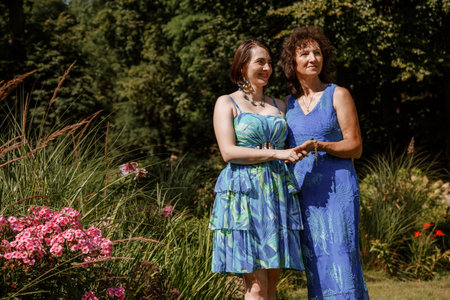 Happy woman have fun in evening gown. Mom and her daughter laughing and walking at the park. Two middle aged women chatting and looking at each other dressed in long dresses. Mother and daughter.の写真素材
