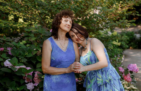 Happy woman have fun in evening gown. Mom and her daughter laughing and walking at the park. Two middle aged women chatting and looking at each other dressed in long dresses. Mother and daughter.の写真素材
