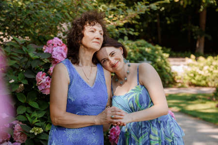 Happy woman have fun in evening gown. Mom and her daughter laughing and walking at the park. Two middle aged women chatting and looking at each other dressed in long dresses. Mother and daughter.の写真素材