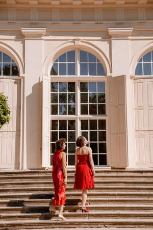 Happy woman have fun in evening gown. Mom and her daughter laughing and walking at the park. Two middle aged women chatting and looking at each other dressed in long dresses. Mother and daughter.の写真素材
