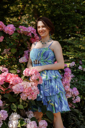 Portrait of an attractive woman gardener. Beautiful European woman in the garden near the flowers. Senior woman without makeup in the garden. Warsaw. Poland.の写真素材
