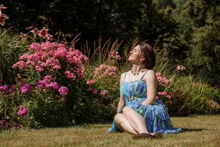 Portrait of an attractive woman gardener. Beautiful European woman in the garden near the flowers. Senior woman without makeup in the garden. Warsaw. Poland.の写真素材