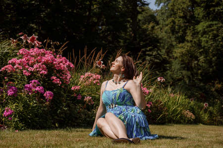 Portrait of an attractive woman gardener. Beautiful European woman in the garden near the flowers. Senior woman without makeup in the garden. Warsaw. Poland.の写真素材