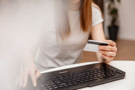 Young woman is holding credit card and using a laptop. Online shopping concept. The girl is doing...