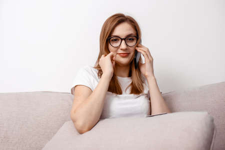 Happy girl sit living room couch speak phone relax. Excited young woman reading unexpected good...
