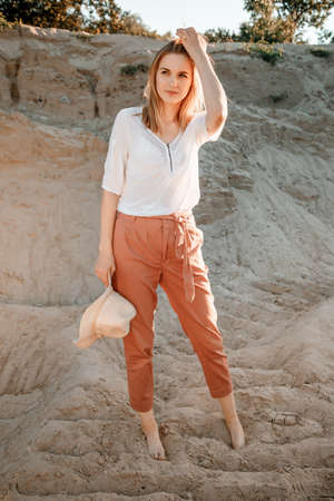 Young beautiful lonely woman with long hair in with straw hat. A lonely girl goes down the sand dunes. Summer fashion portrait outdoor.の写真素材