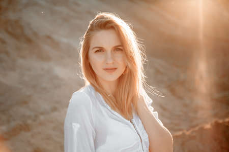 Young beautiful lonely woman with long hair in with straw hat. A lonely girl goes down the sand dunes. Summer fashion portrait outdoor.の写真素材