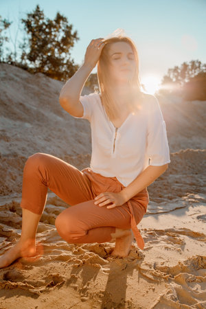 Young beautiful lonely woman with long hair in with straw hat. A lonely girl goes down the sand dunes. Summer fashion portrait outdoor.の写真素材