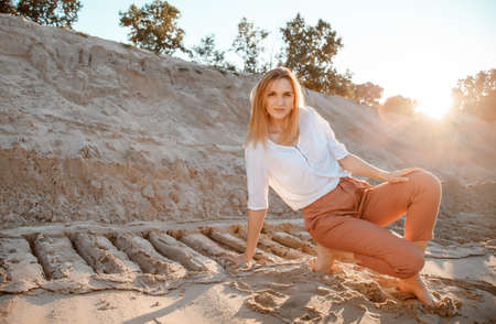 Young beautiful lonely woman with long hair in with straw hat. A lonely girl goes down the sand dunes. Summer fashion portrait outdoor.の写真素材