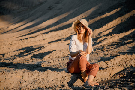 Young beautiful lonely woman with long hair in with straw hat. A lonely girl goes down the sand dunes. Summer fashion portrait outdoor.の写真素材