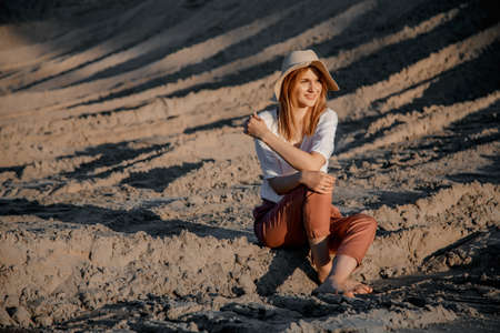 Young beautiful lonely woman with long hair in with straw hat. A lonely girl goes down the sand dunes. Summer fashion portrait outdoor.の写真素材
