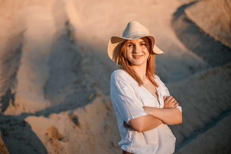 Young female exploring sandy beach with hat. Hipster girl, young traveler in nature desert. A woman walks in the desert to meet.の写真素材