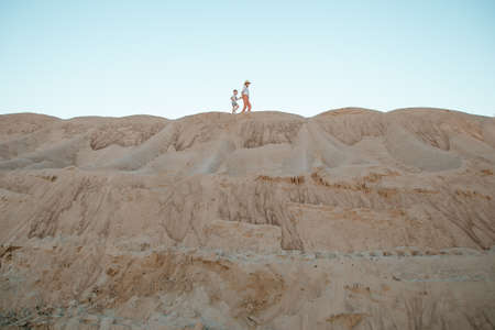 Woman being kissed by her loving son during sunset. Mother with her son on sand dune. Travel.の写真素材