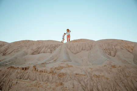 Woman being kissed by her loving son during sunset. Mother with her son on sand dune. Travel.の写真素材